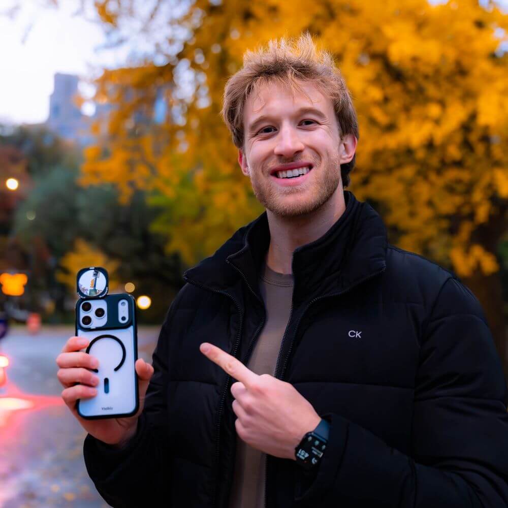Man smiling holding MirrorMe mirror phone case in Central Park