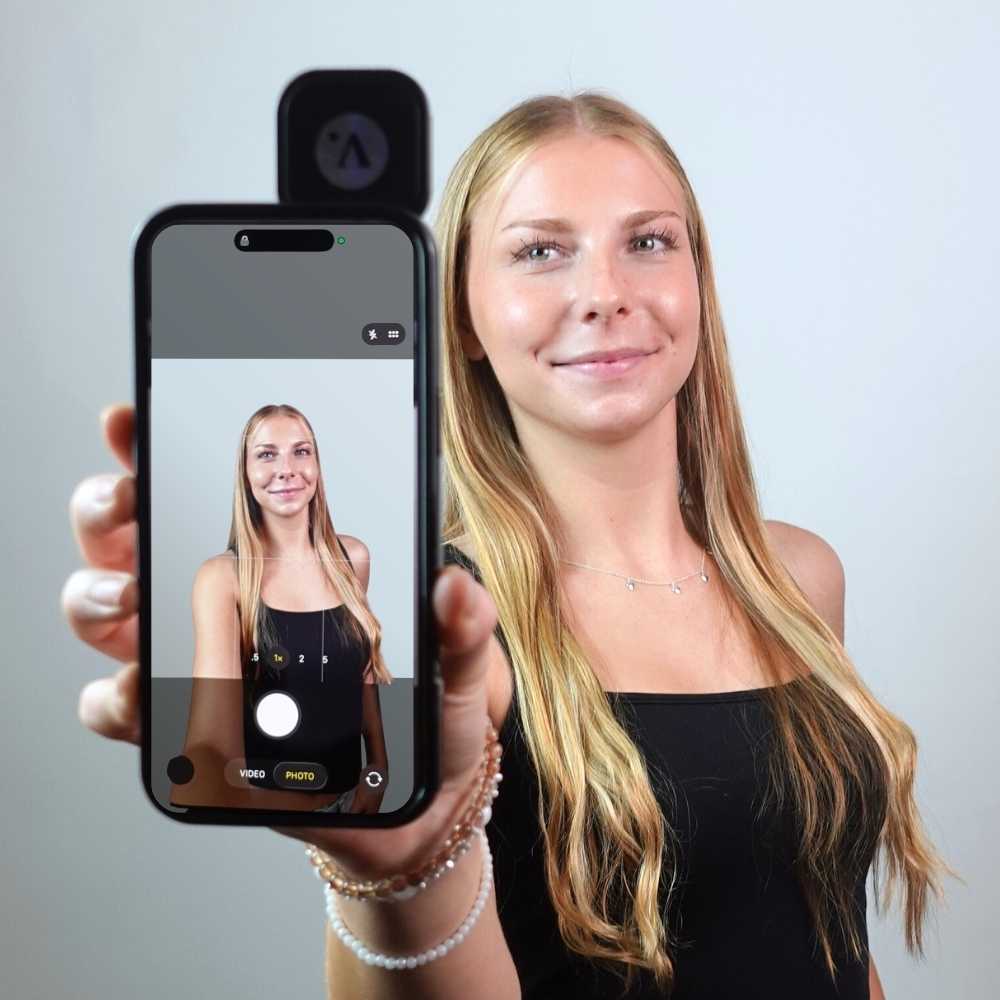 Person holding a mirror phone case with the camera app open.