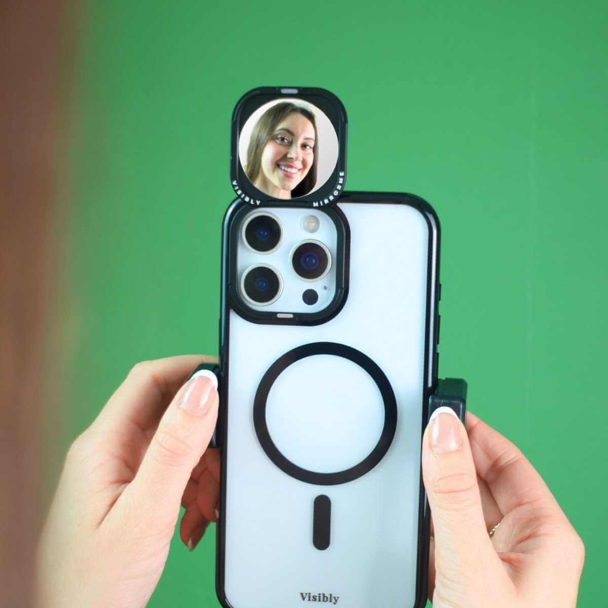 Smiling woman using a mirror phone case as a content creation tool to help her film